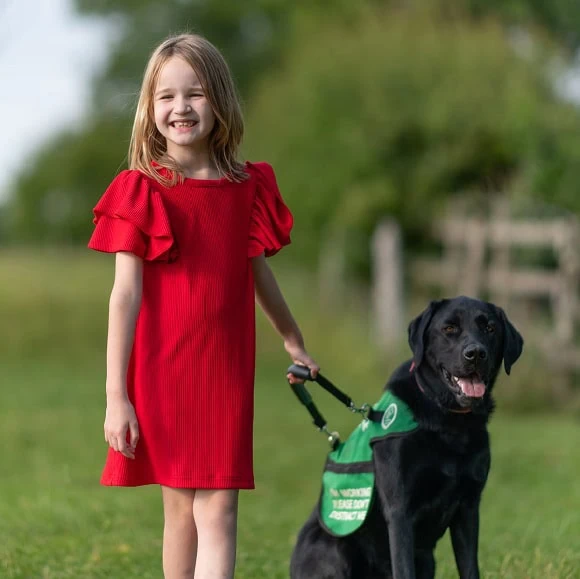 Autism Assistance Black Labrador Child Field Bonding Smiling Frontfacing Closeup