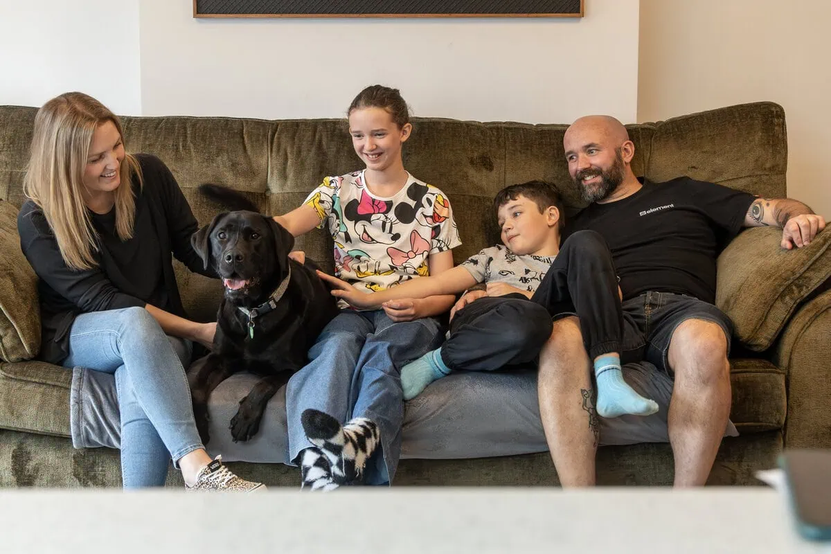 Family Sofa Parents Children Black Labrador Relaxed Smiling Frontfacing
